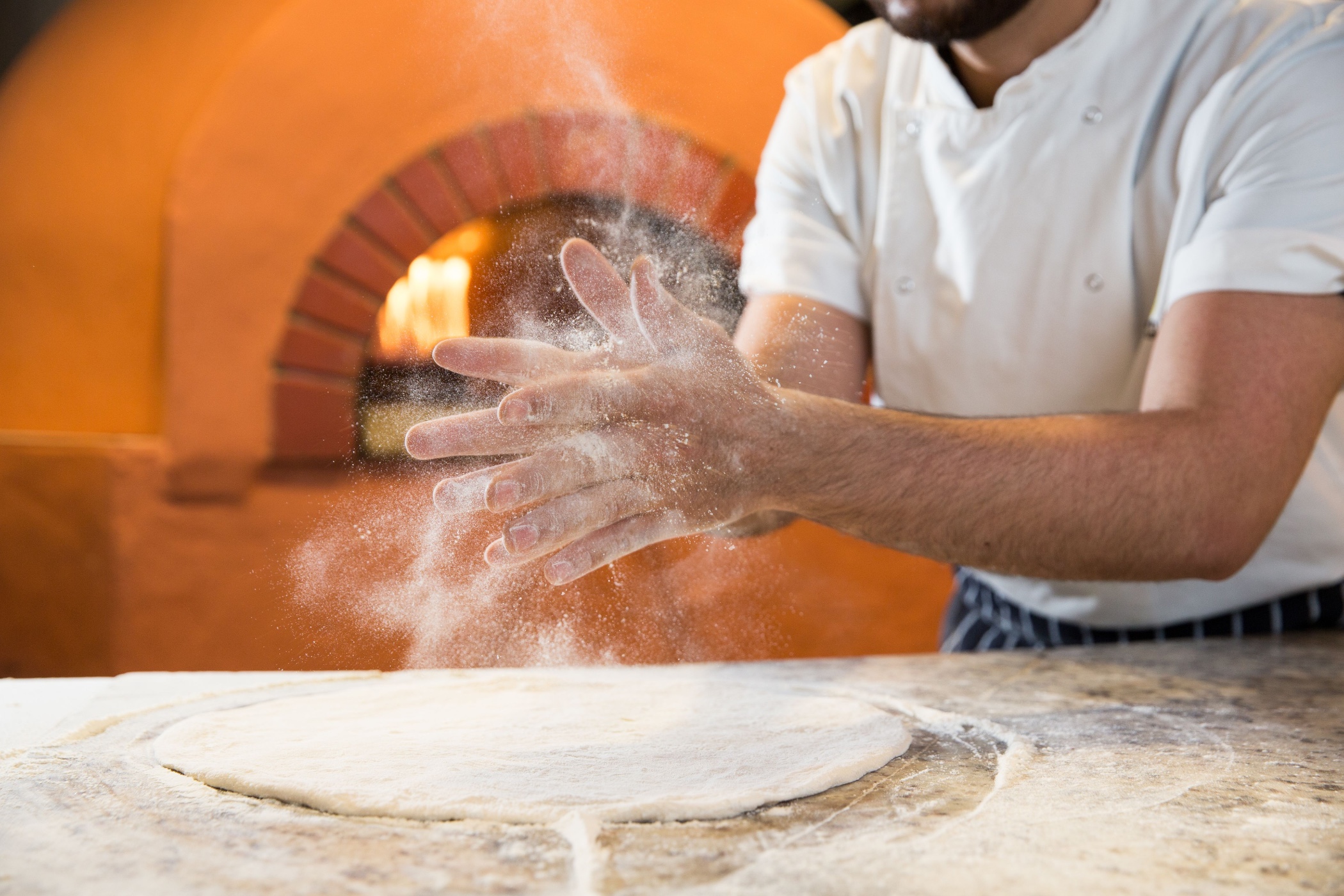 A chef claps his hand spreading flour into the air