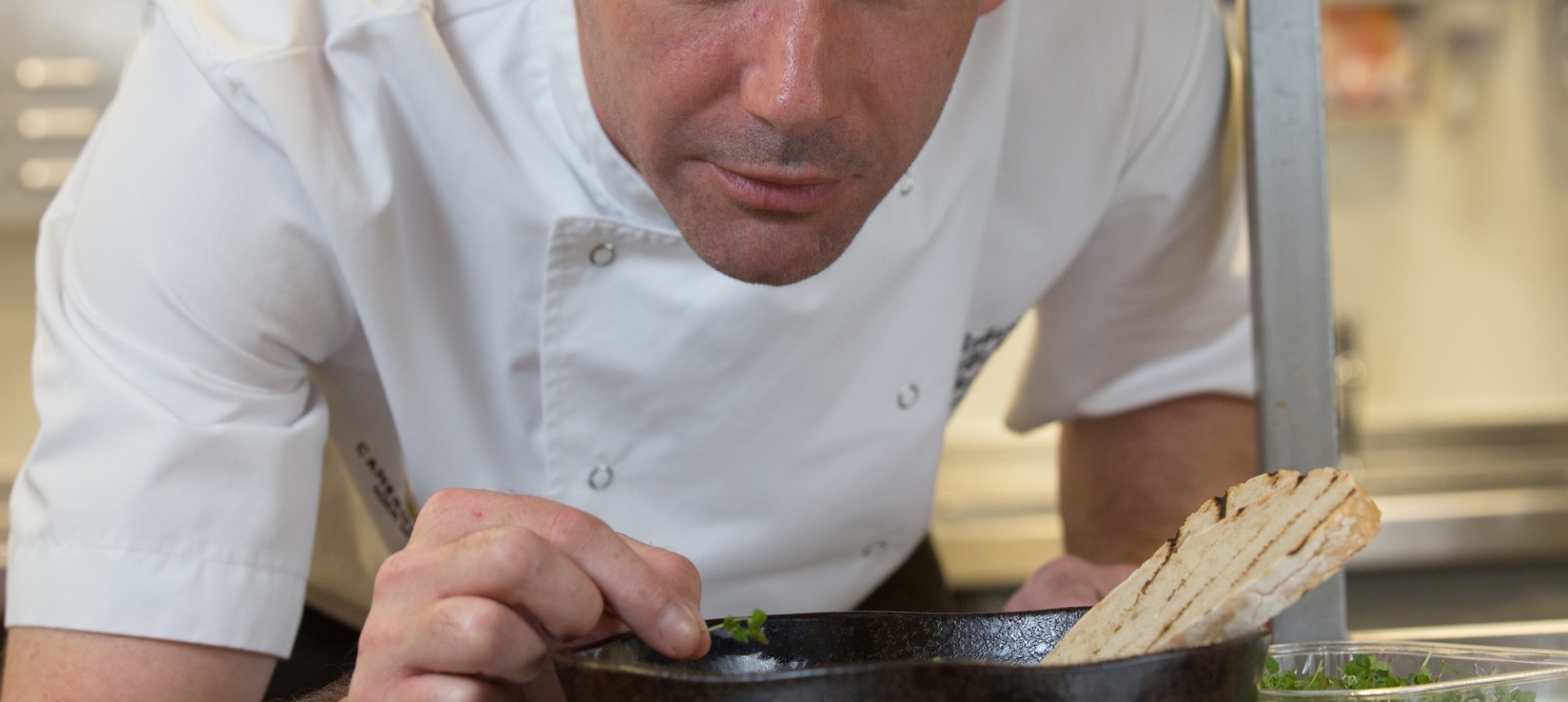 A chef delicately places the finishing touches on an entrée