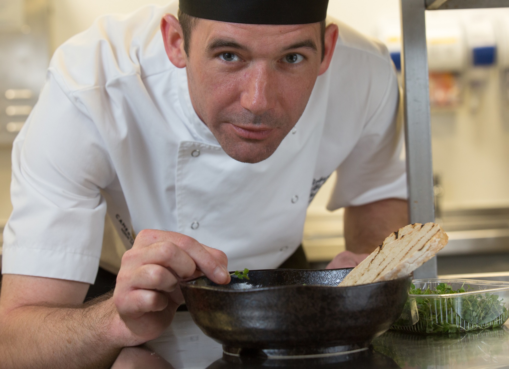 A chef delicately places the finishing touches on an entrée