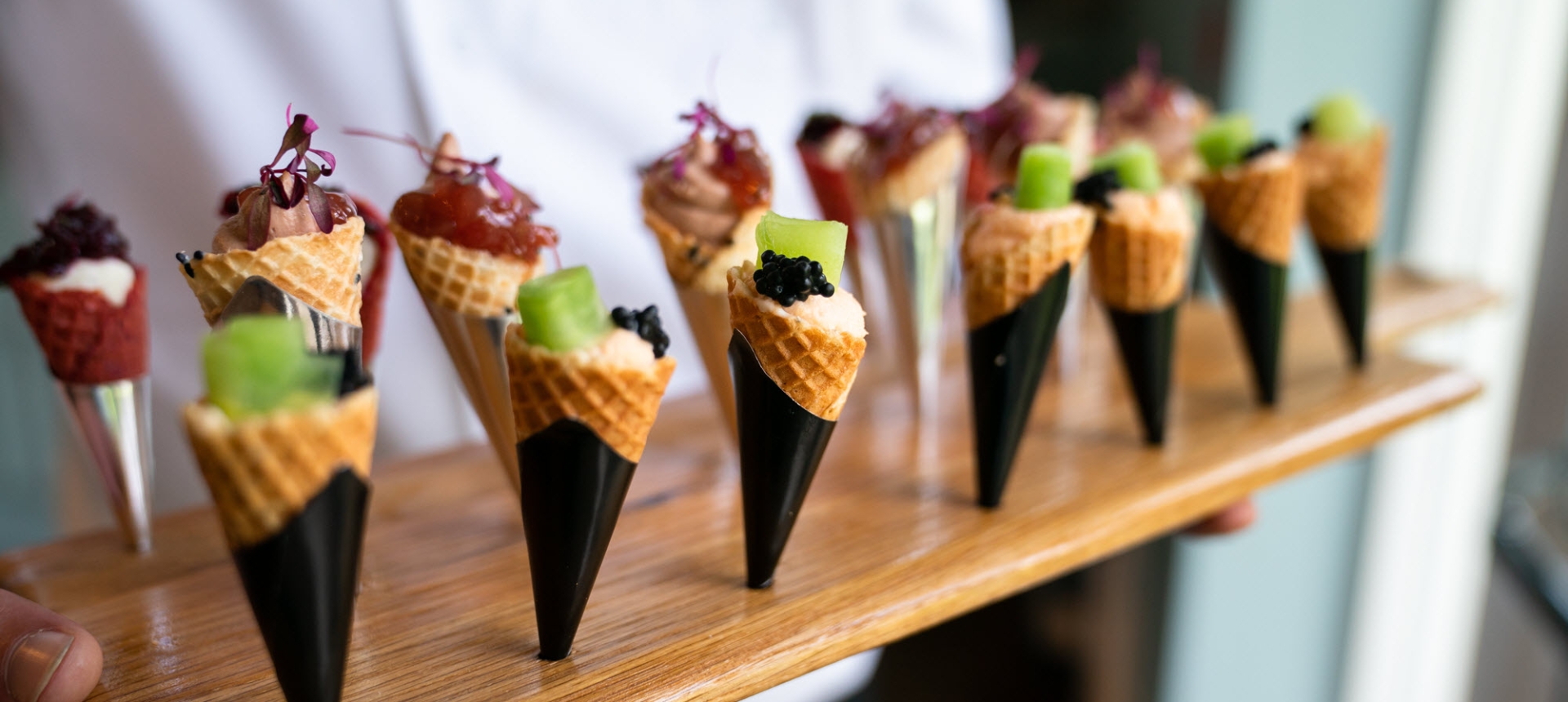 a chef holds a tray of appetizers shaped like cones