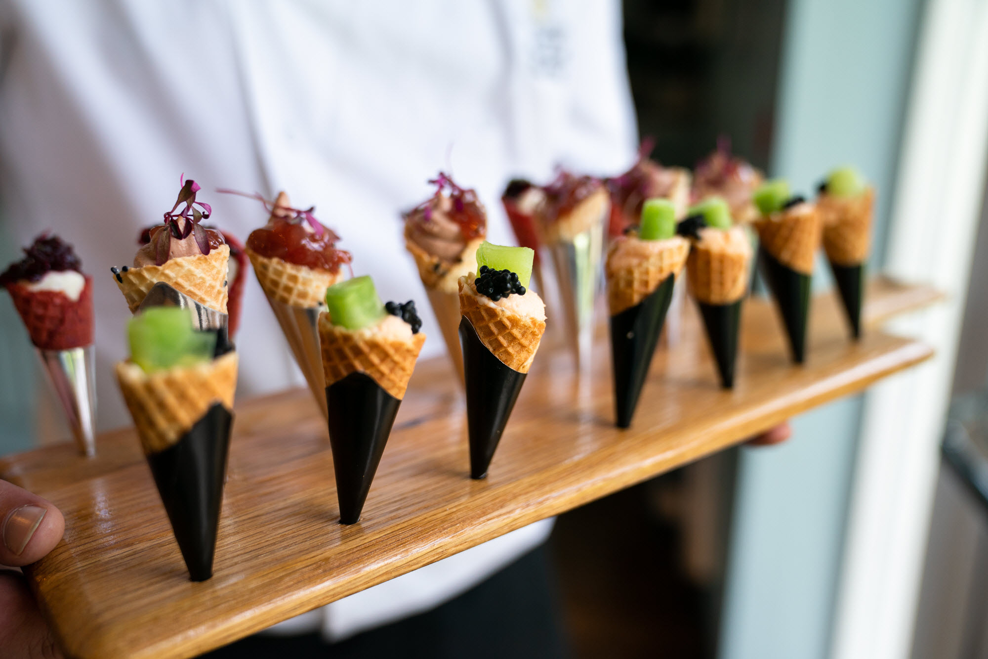 a chef holds a tray of appetizers shaped like cones