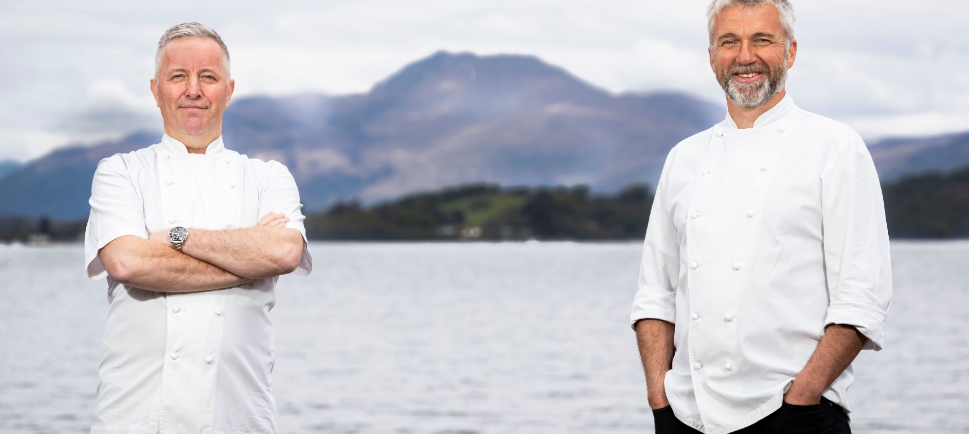 Chefs Martin Wishart and Paul Tamburrini in their chef coats standing in front of Loch Lomond