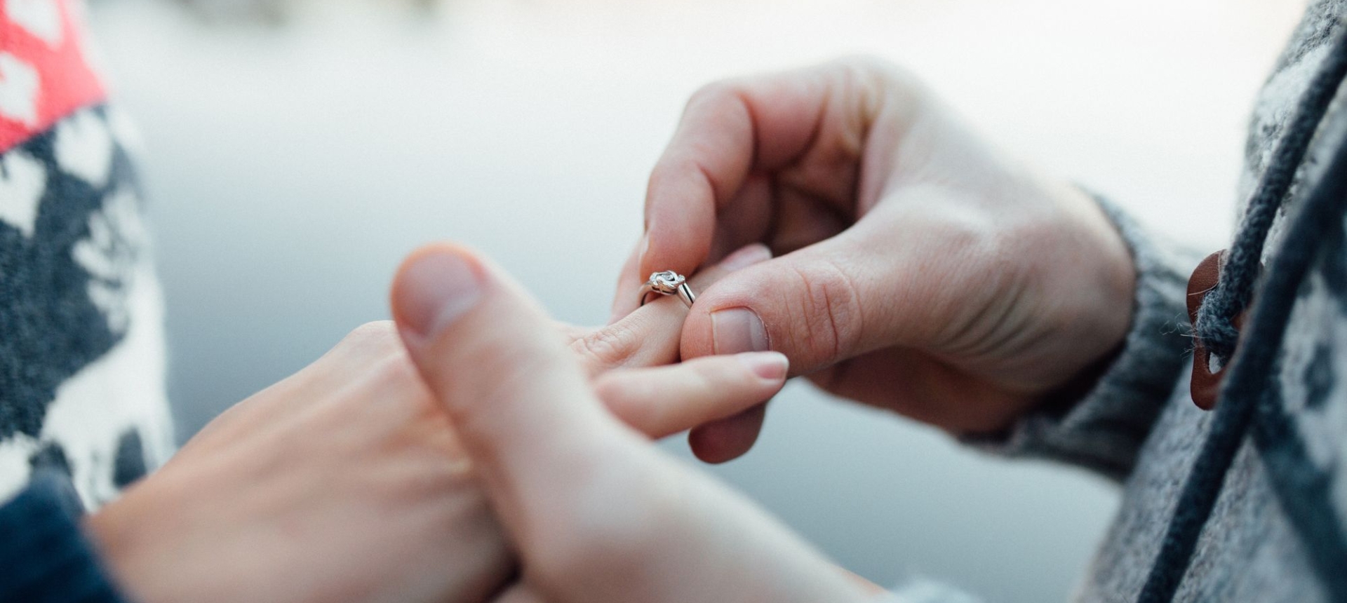 A man putting an engagement ring on a woman's hand