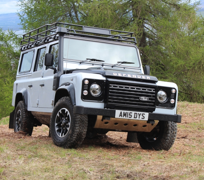 a white SUV sitting on a patch of grass with trees in the background