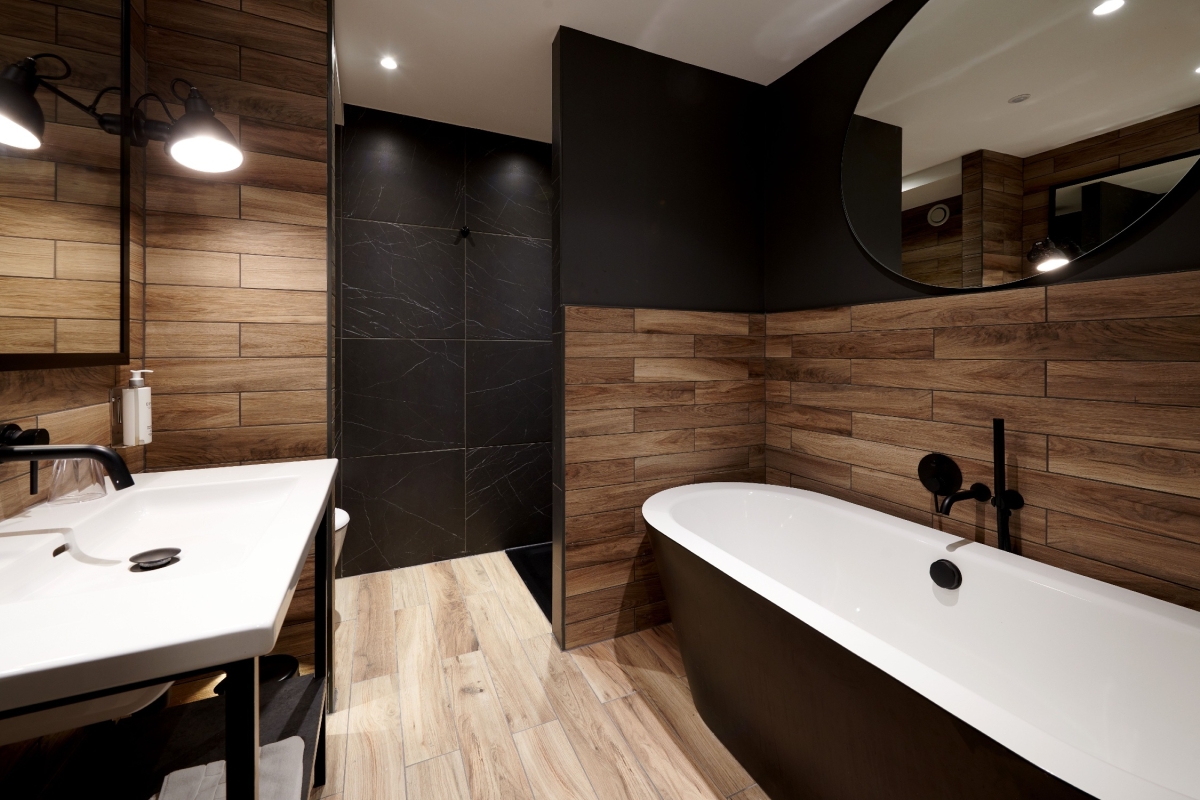 Modern bathroom with wooden wall and black fixtures.