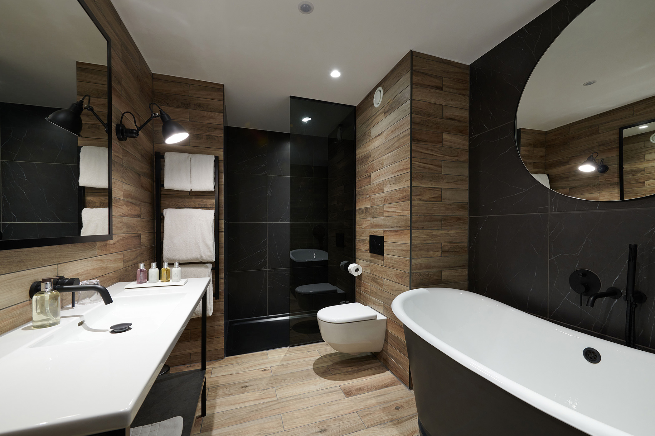 a bathroom with a full sized black tub leading and a toilet and shower area
