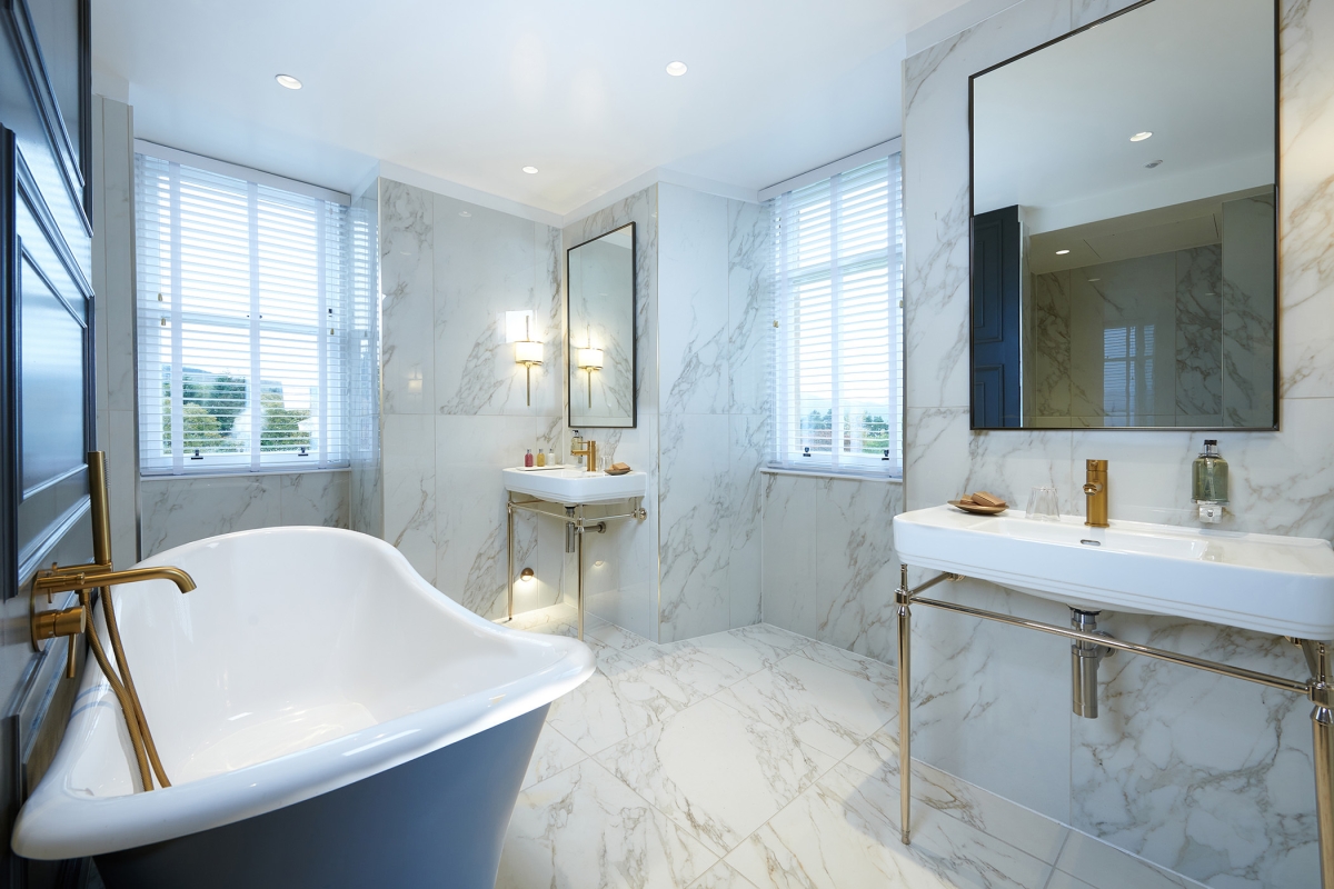 a beautiful marble bathroom with a full sized tub and two sinks