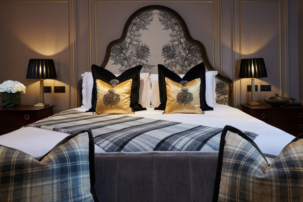 a bed with gold and black pillows and a massive head board