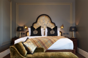 master bed with a gold lounge chair and black pillows on the bed