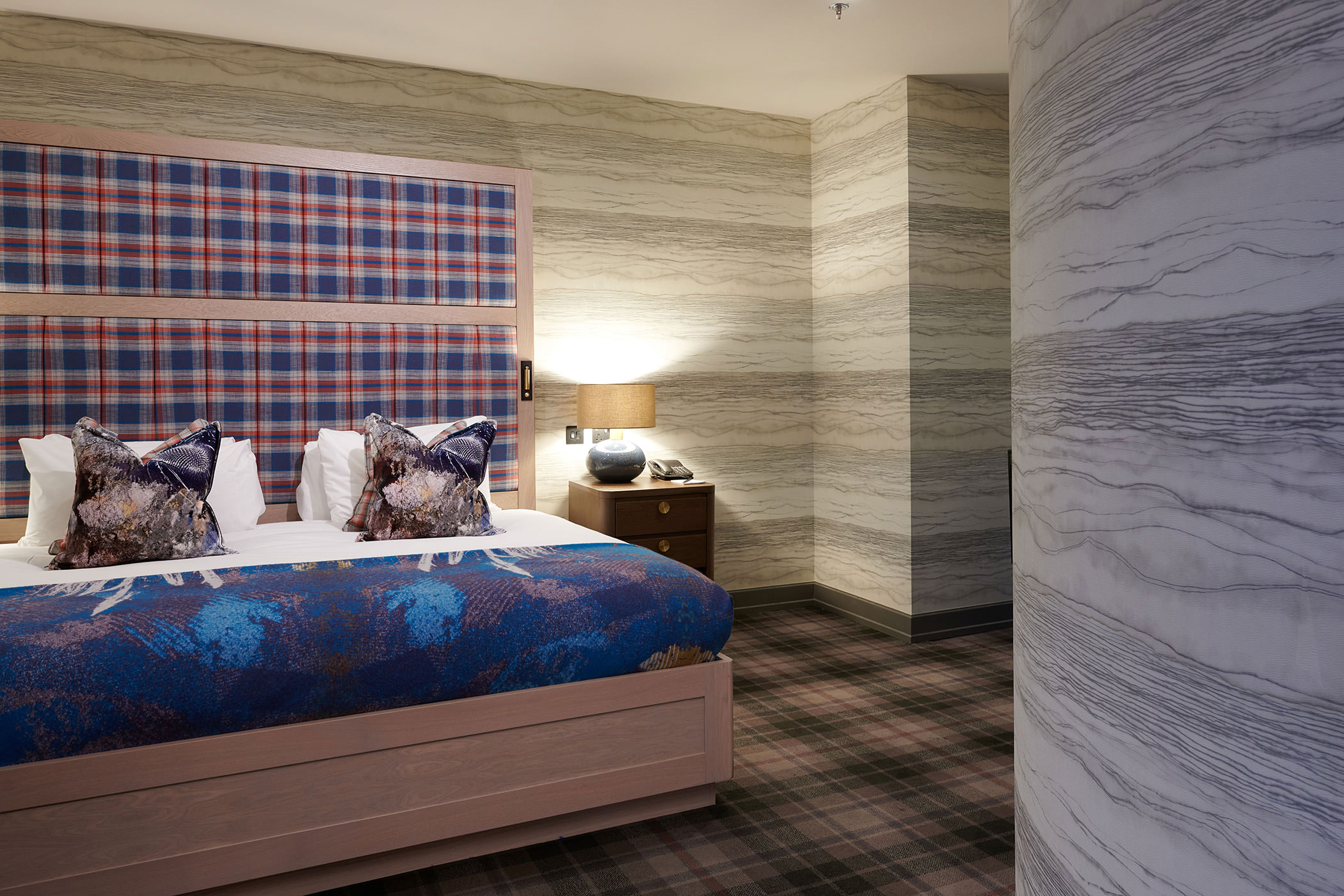 a large bed next to a night stand in a bed room