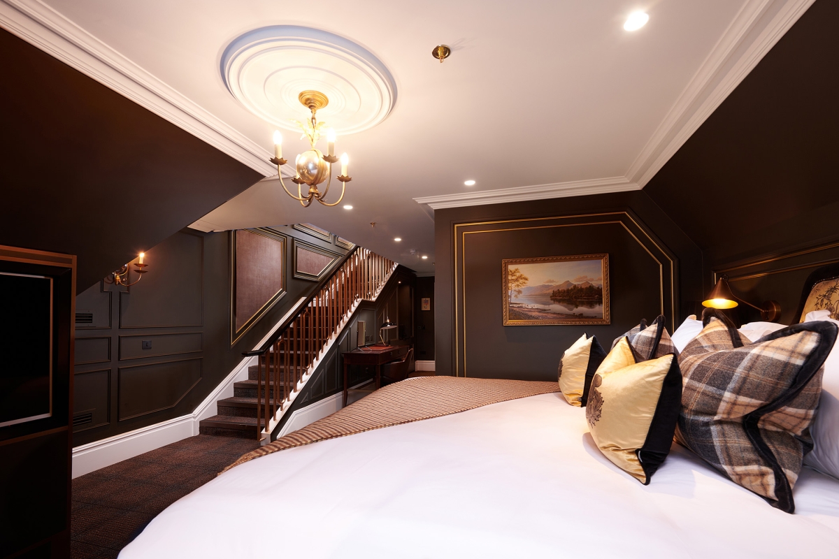 a large bed in a room with stairs leading to an upper level
