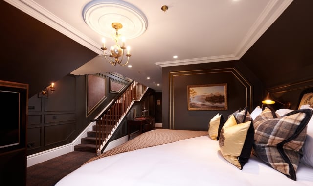 a large bed in a room with stairs leading to an upper level