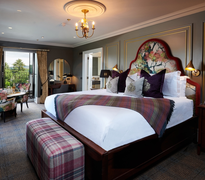 a large floral pattern bed with floral chairs surrounding a table and a door way to a patio