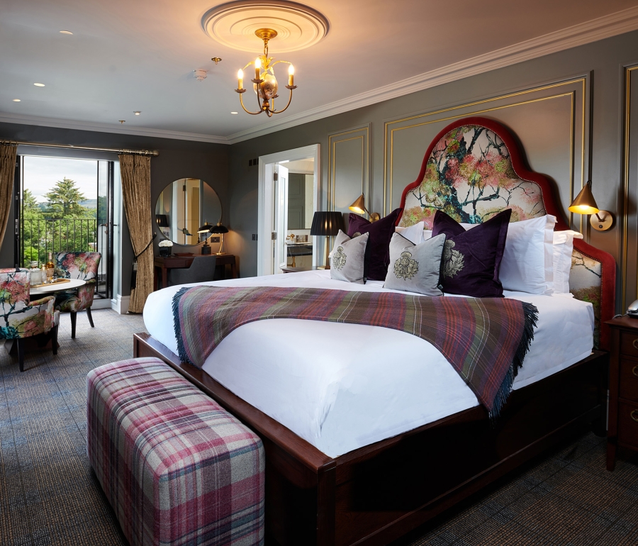 a large floral pattern bed with floral chairs surrounding a table and a door way to a patio