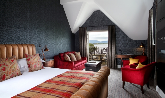 a bed sitting in a bed room with a red couch and two red chairs in front of a patio sitting area