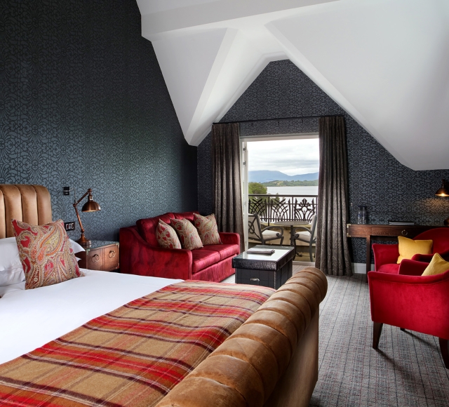 a bed sitting in a bed room with a red couch and two red chairs in front of a patio sitting area