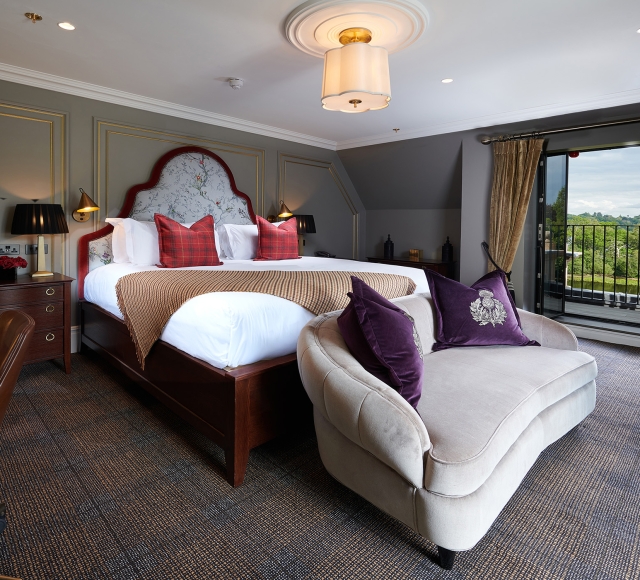 a large bed in a bed room with a couch in front of the bed a patio over looking the water