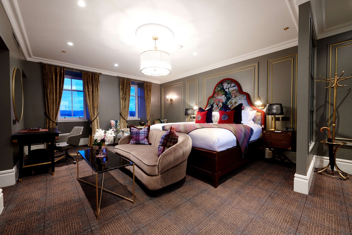 a bed room with a bright red trim around the head board and red pillows with couches and tables in front