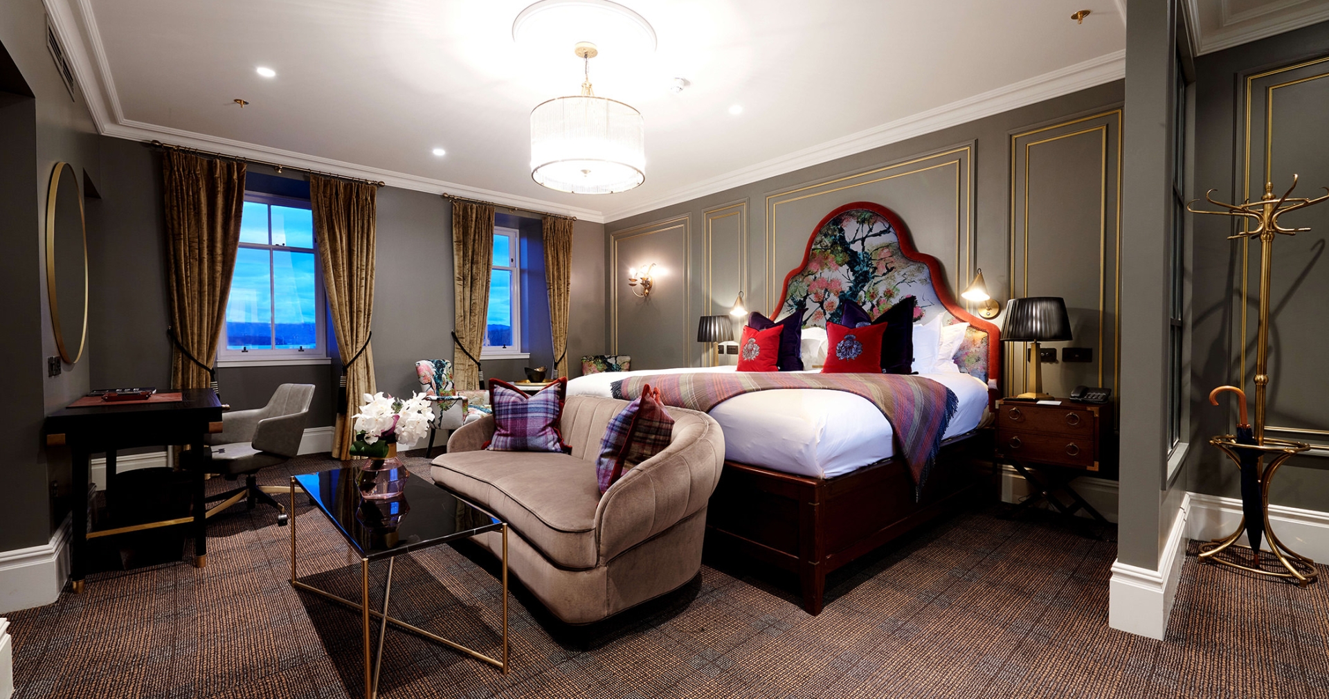 a bed room with a bright red trim around the head board and red pillows with couches and tables in front