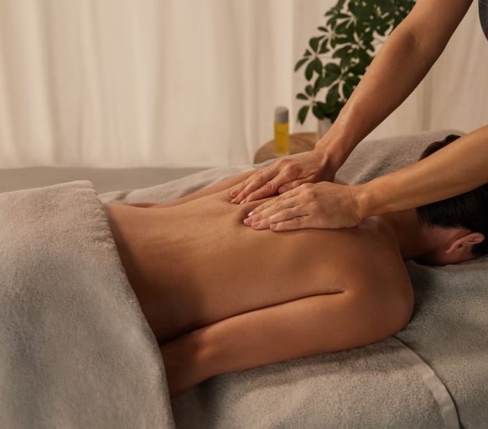 a woman laying face down getting her shoulders massaged