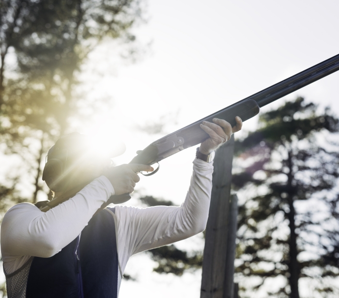 a man holding a shotgun shooting clay targets