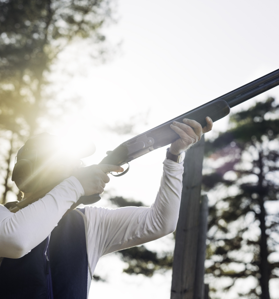 a man holding a shotgun shooting clay targets