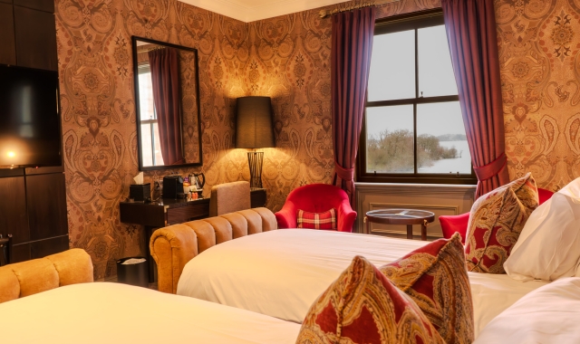 Twin beds in a hotel room with a window overlooking Loch Lomond at Cameron House.