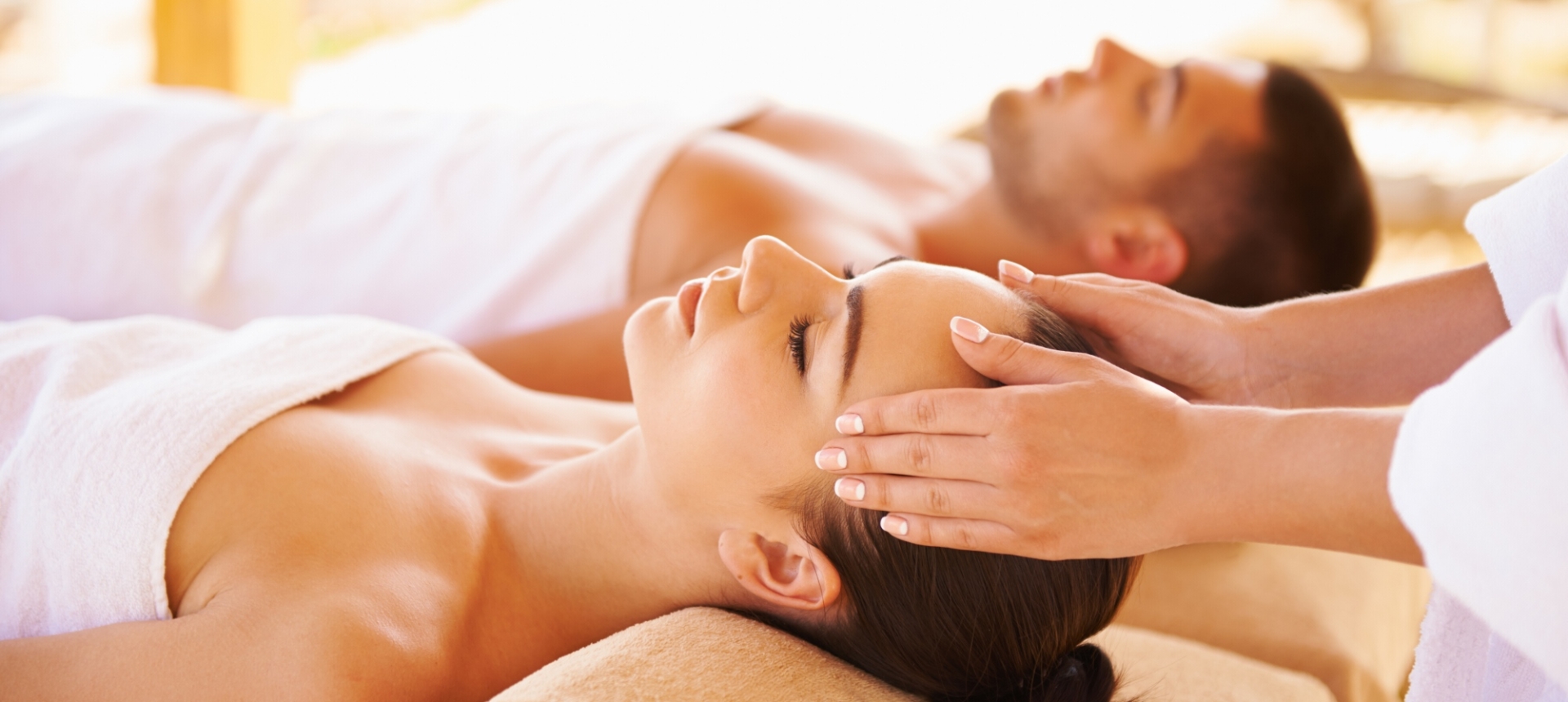 a couple laying side by side while the woman gets her temple massaged