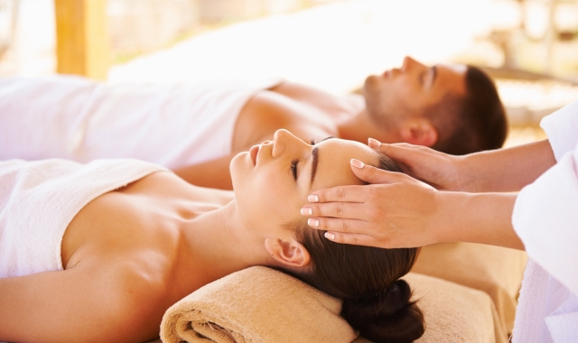 a couple laying side by side while the woman gets her temple massaged