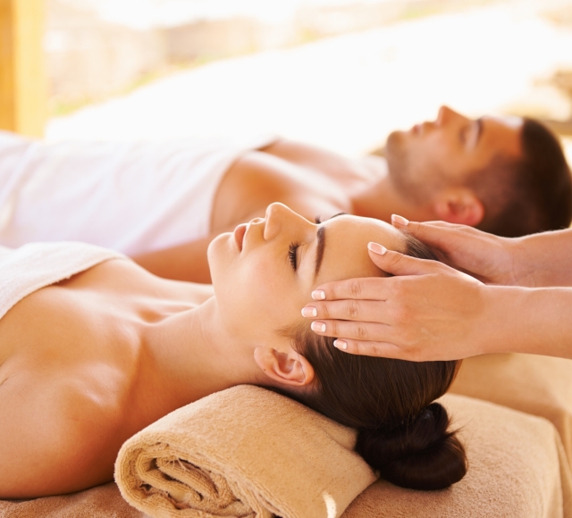 a couple laying side by side while the woman gets her temple massaged