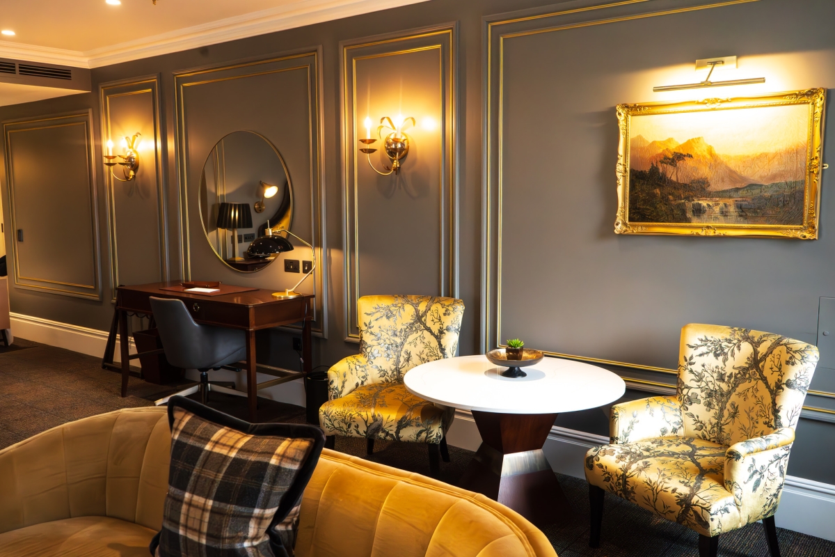 a business desk beside two comfortable and upscale seating chairs and plush yellow sofa in the loch view suite in Auld House.