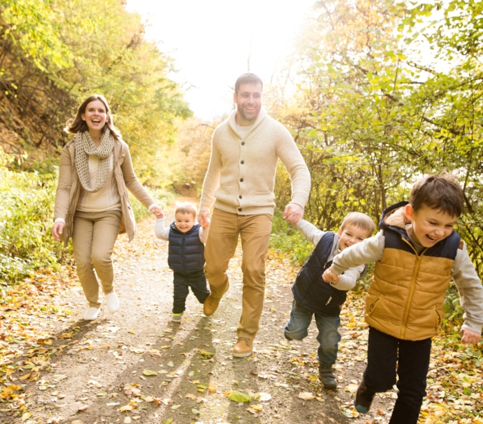 a family walking down a trail in the forest laughing on a sunny day