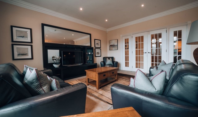 a living room area with black couches and a tv for entertainment