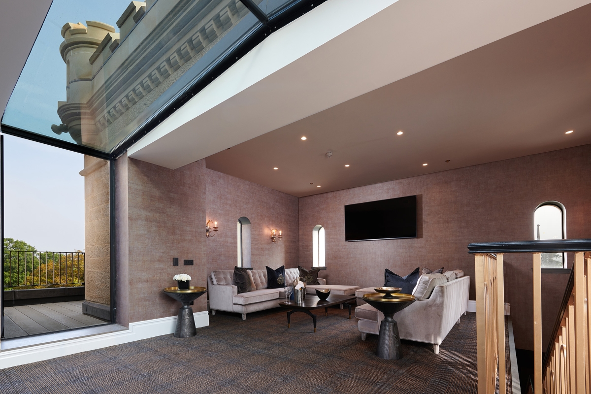 a sitting area in the corner of the room with a tv mounted to the wall and a glass ceiling