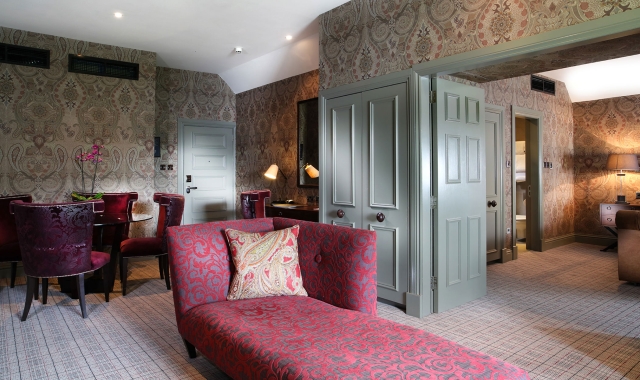 a floral themed lounge chair sitting in front of a open door way leading to a bed room