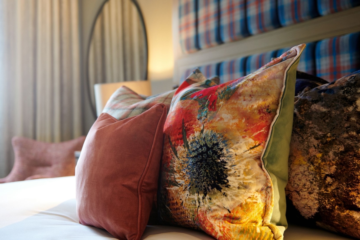 Colourful hotel room pillows with flowers.