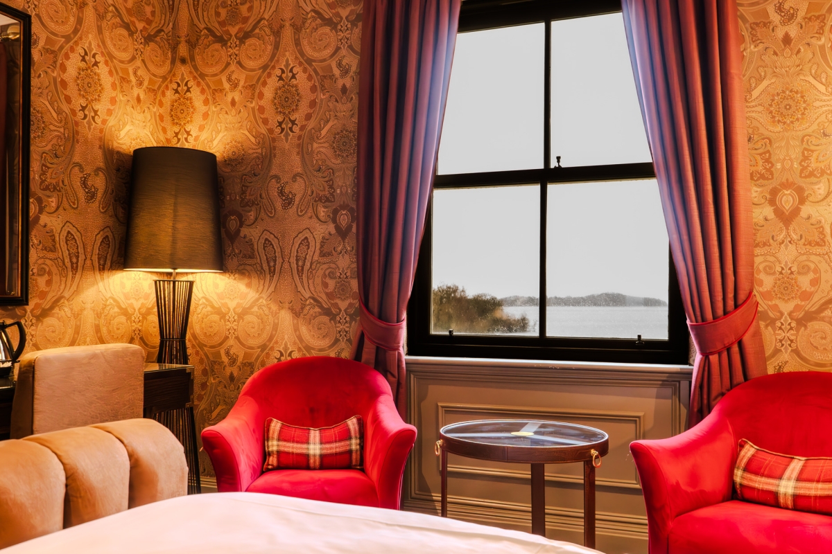 Comfortable hotel room with bed, chair, and window that overlooks Loch Lomond
