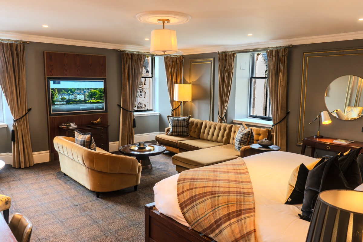 a living area in the loch view suite at Auld House with two sofas, a coffee table, flatscreen tv and large windows.