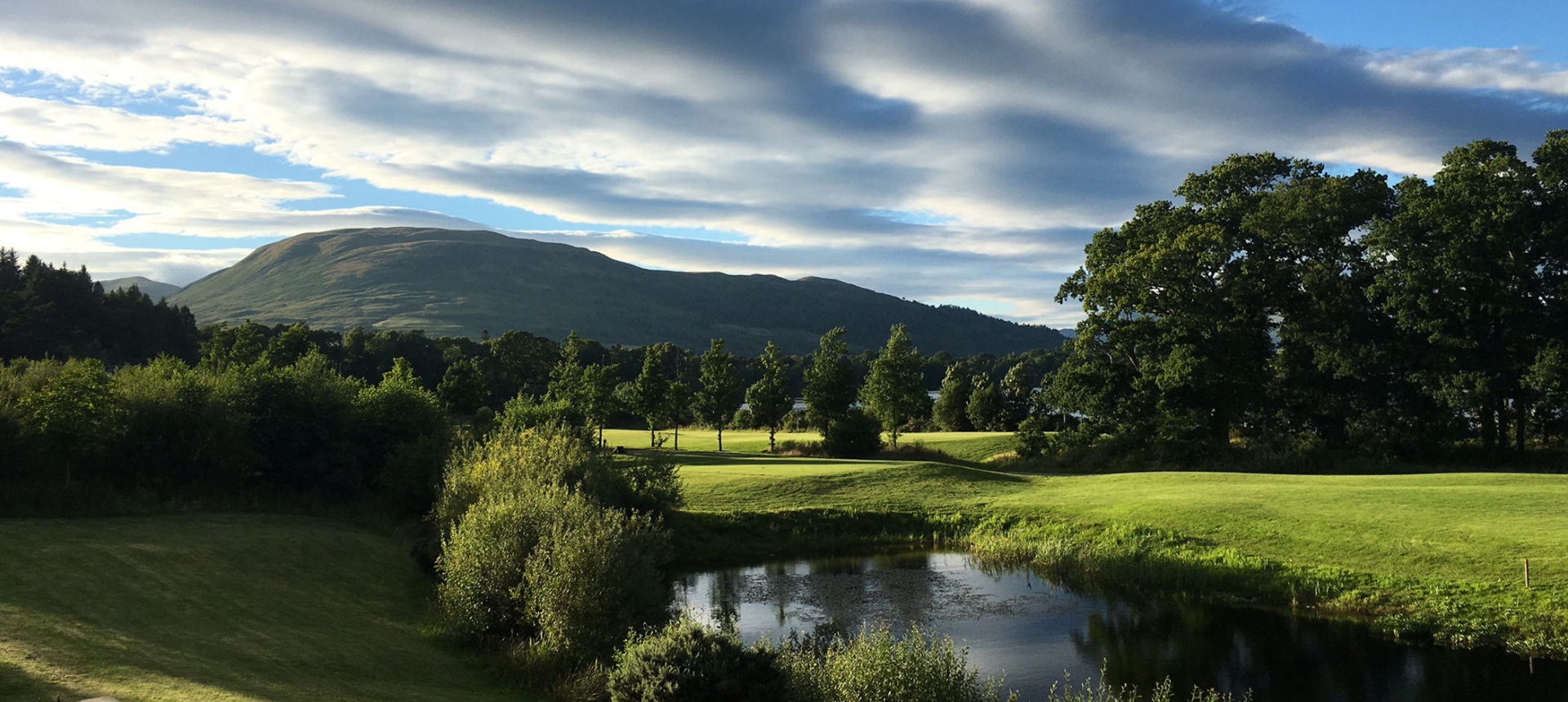 a view from cameron house over looking the green grass and a large mountain in the back