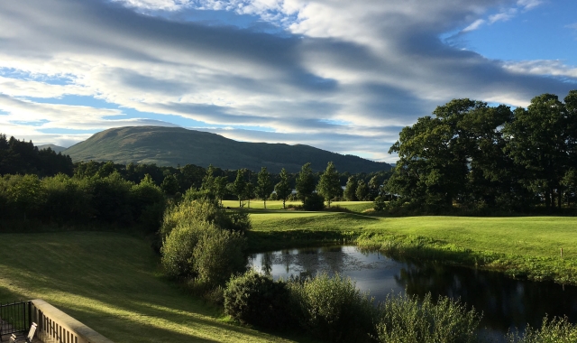 a view from cameron house over looking the green grass and a large mountain in the back