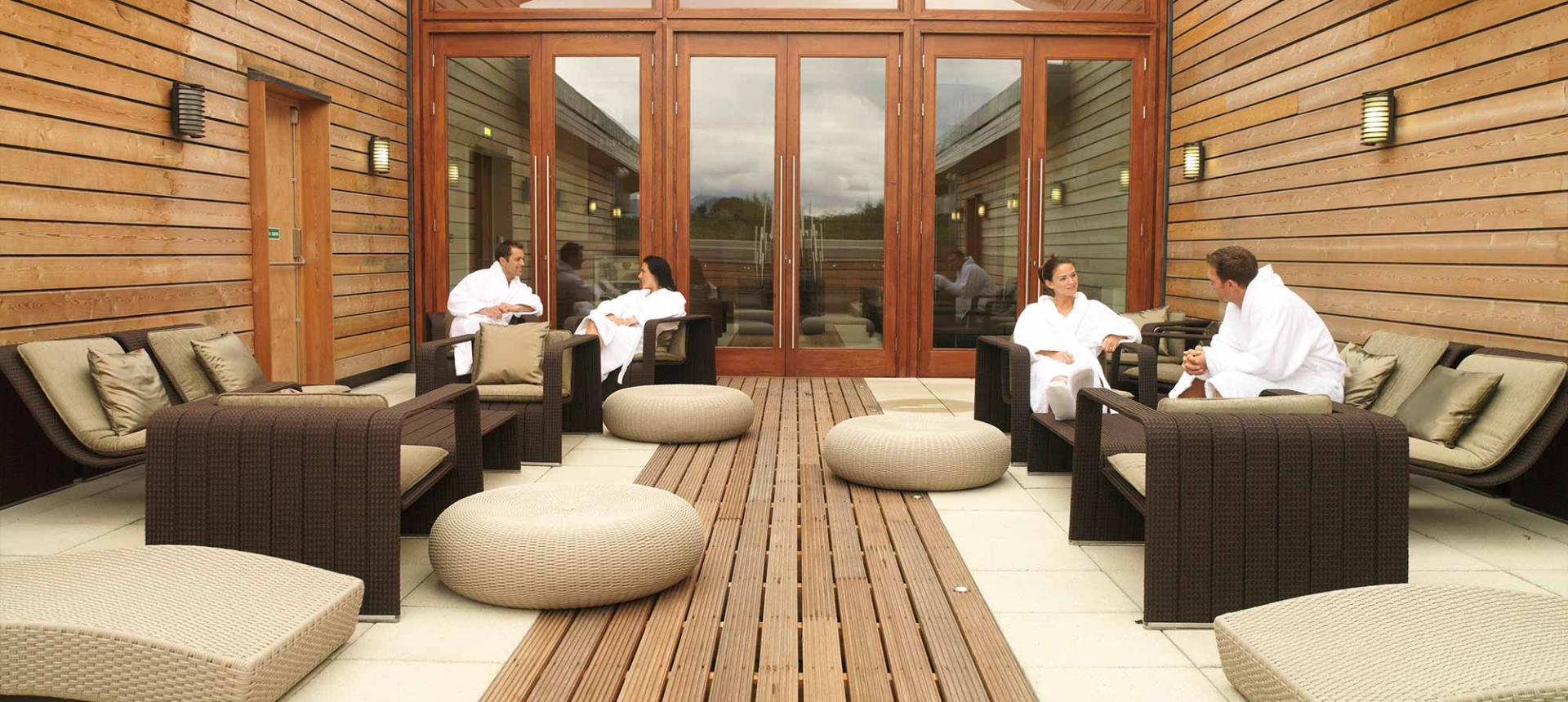 people sitting outside in robes enjoying the sun in the spa area