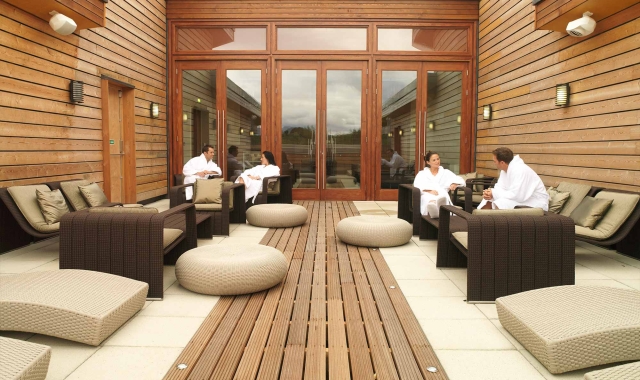 people sitting outside in robes enjoying the sun in the spa area