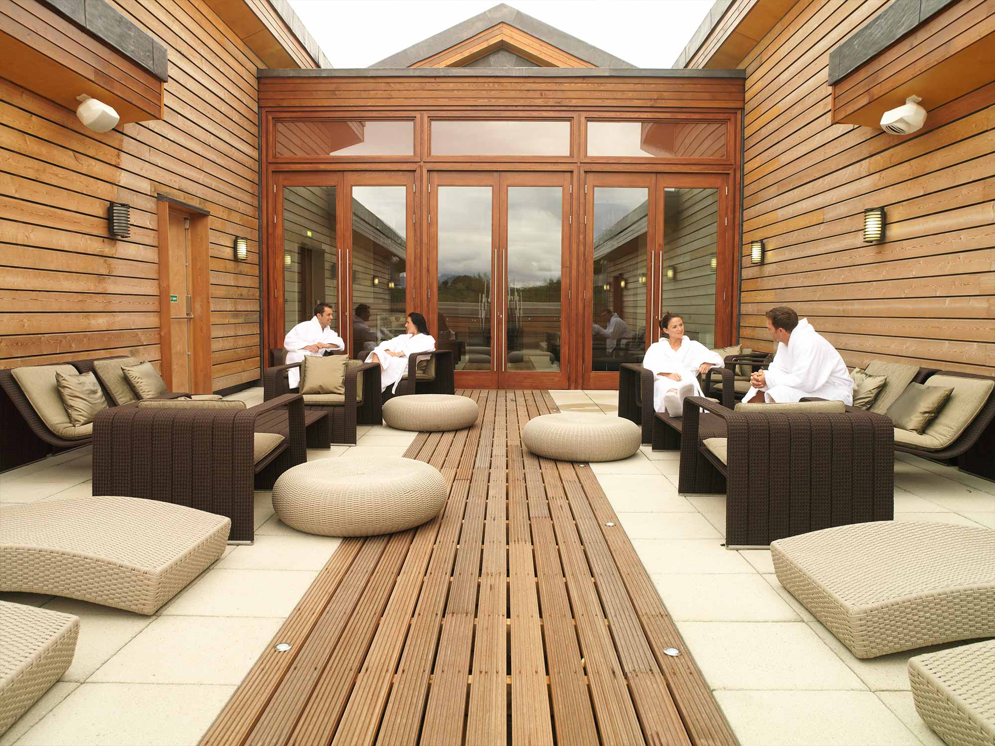 people sitting outside in robes enjoying the sun in the spa area