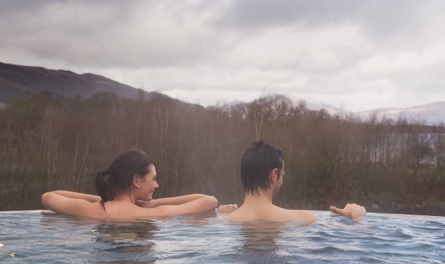 two people in an outdoor infinity pool looking at the forest
