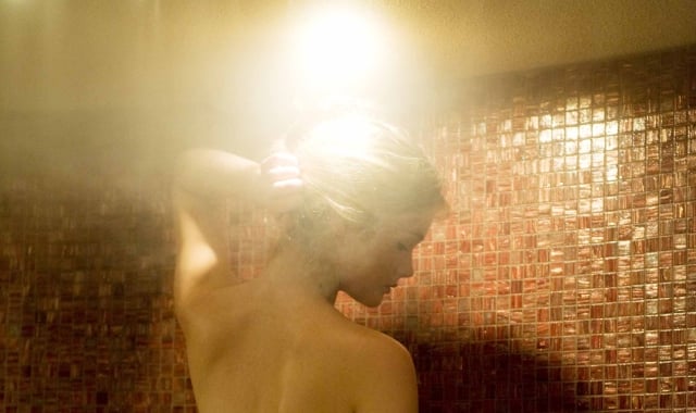 a woman taking a steam shower with red tiles lining the inside of the shower
