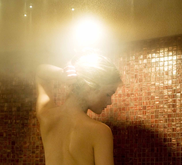 a woman taking a steam shower with red tiles lining the inside of the shower