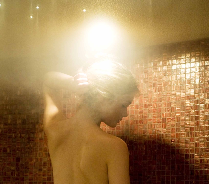 a woman taking a steam shower with red tiles lining the inside of the shower