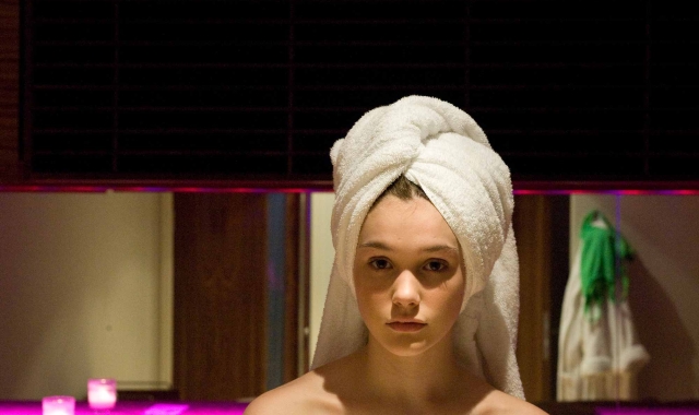 a woman in the spa with a towel wrapped around her head and pink background lighting