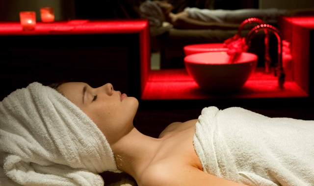 a woman relaxing on a table with red back ground lighting