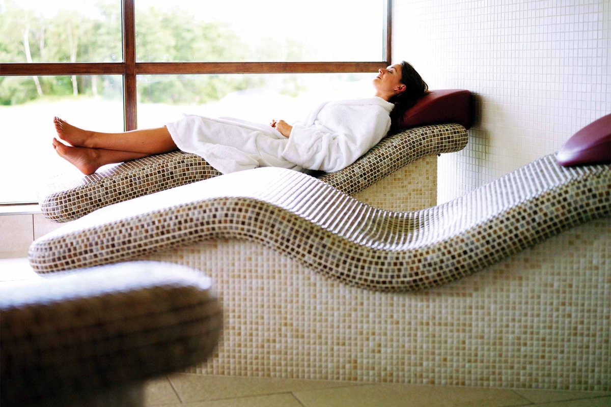 a woman relaxing on a tile chair enjoying the sun shine coming in from the out side